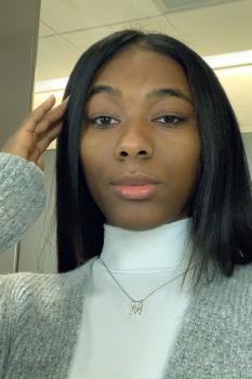 Young woman with straight black hair, wearing a white turtleneck with a grey cardigan