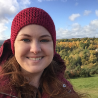 A portrait of a woman wearing a red beanie hat with a forest in the background