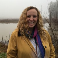 A woman standing in front of a foggy pond