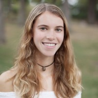 A portrait of Bentley Kandel / a woman wearing a white shirt and a small pendant necklace