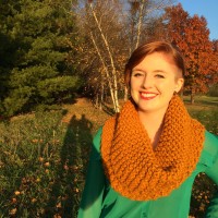 Image of Lizzie Hjelle, red hair with an orange scarf, wearing a green shirt