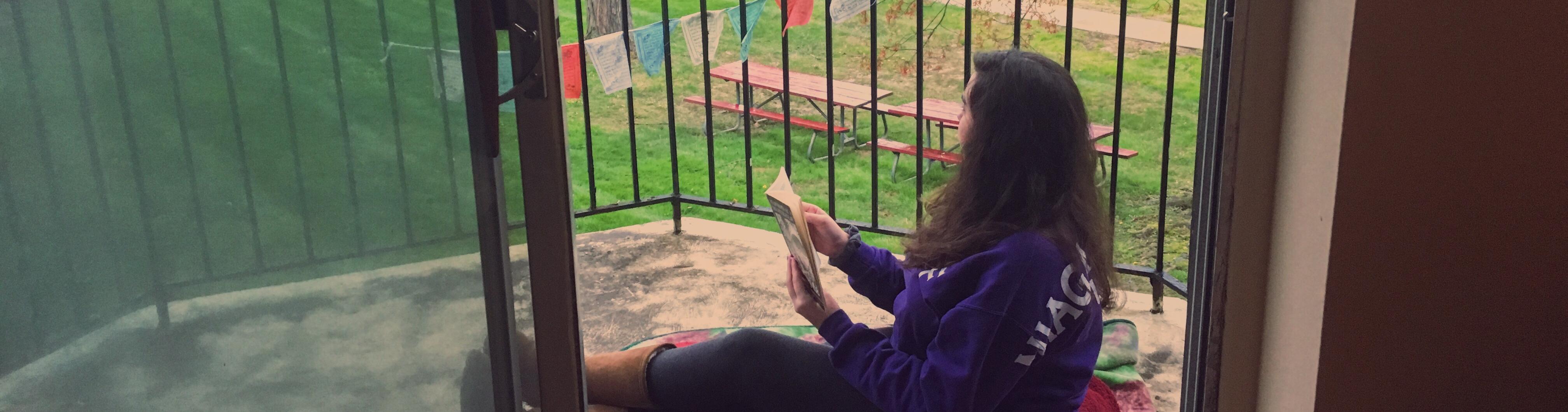 A person reading on a porch from their apartment.