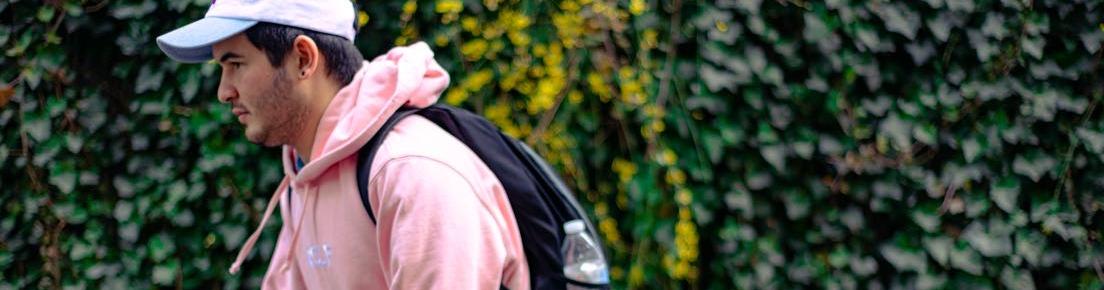 A student in a pink sweatshirt walking across campus in spring