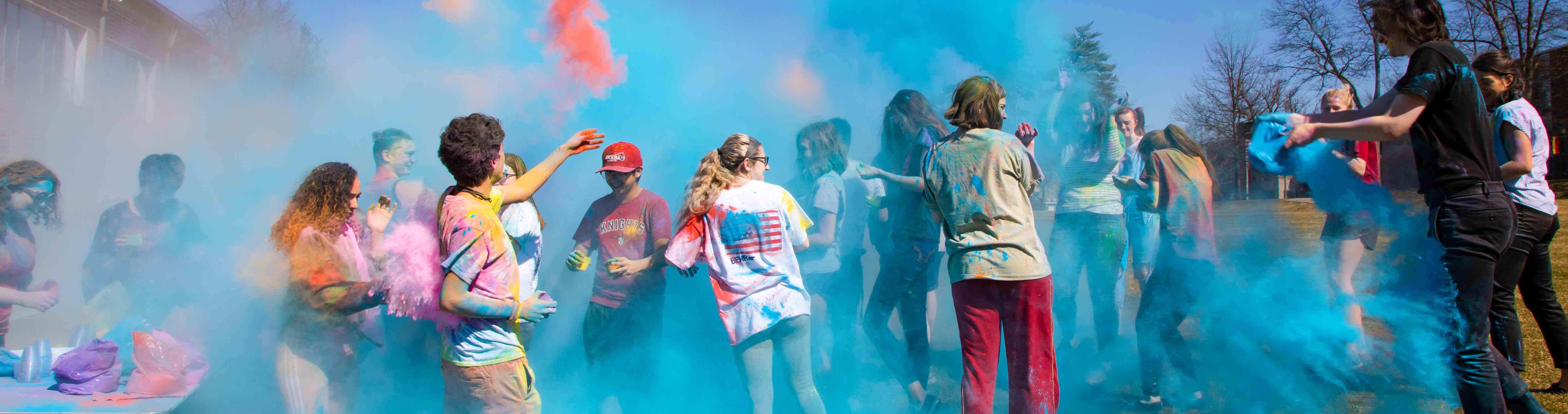 Several students throwing colored powder all over each other