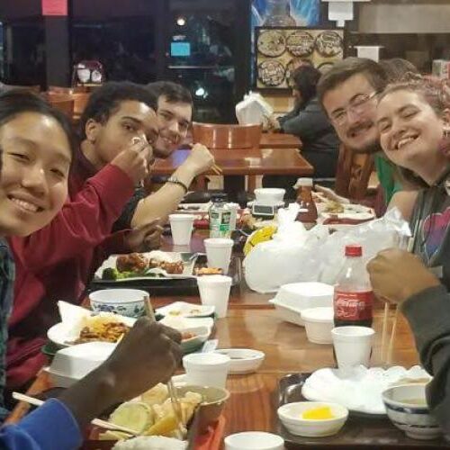 Photo of students smiling and eating at a restaurant.