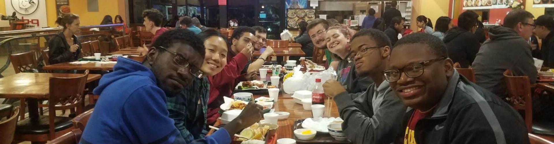 Photo of students smiling and eating at a restaurant.