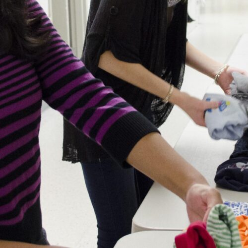 Close up of two students sorting clothes for community outreach program