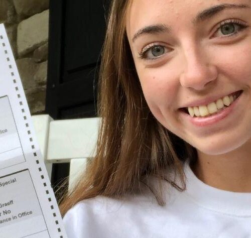 A student holding up a 2020 vote ballot.