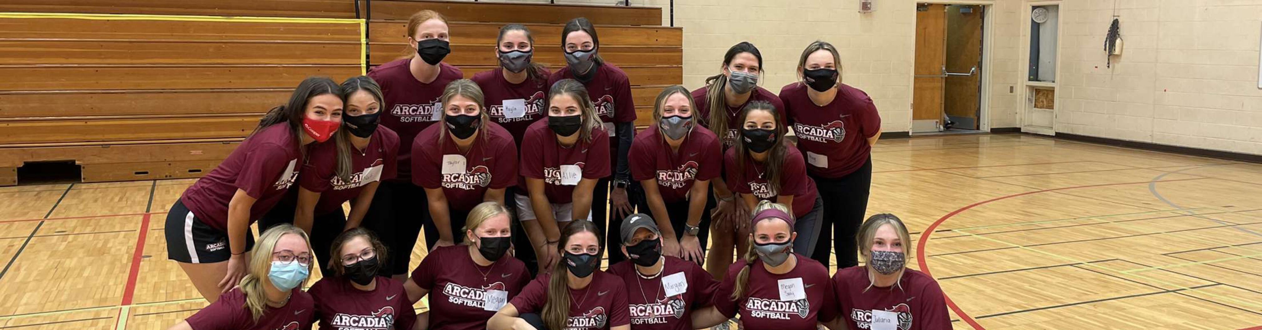 Masked Arcadia girls sports team poses in a huddle in the gym