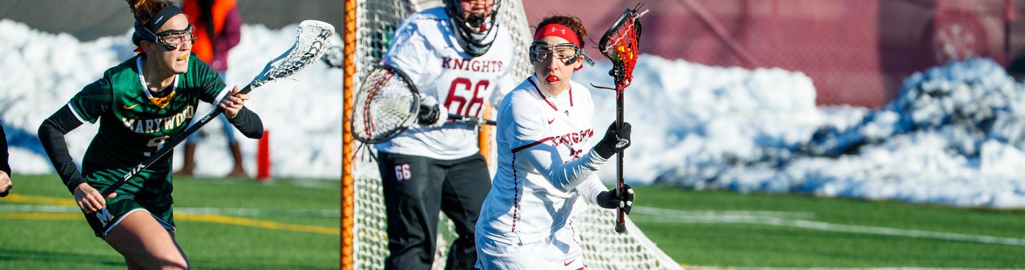 A lacrosse player for Arcadia controls the ball in front of the net vs Marywood