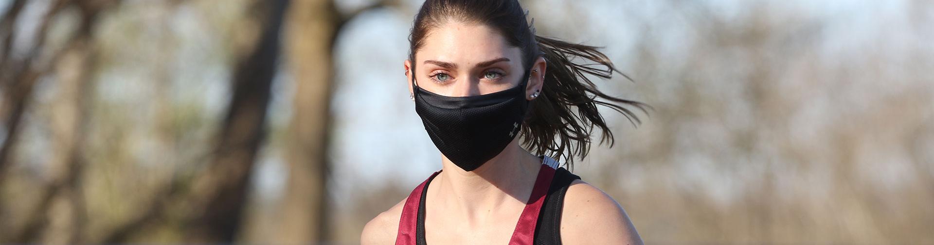 Female student jogging with a black mask on.