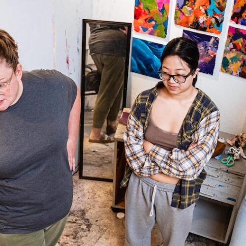 A photo of Krista Profitt and two other women by her side in front of a wall with blue paint on it