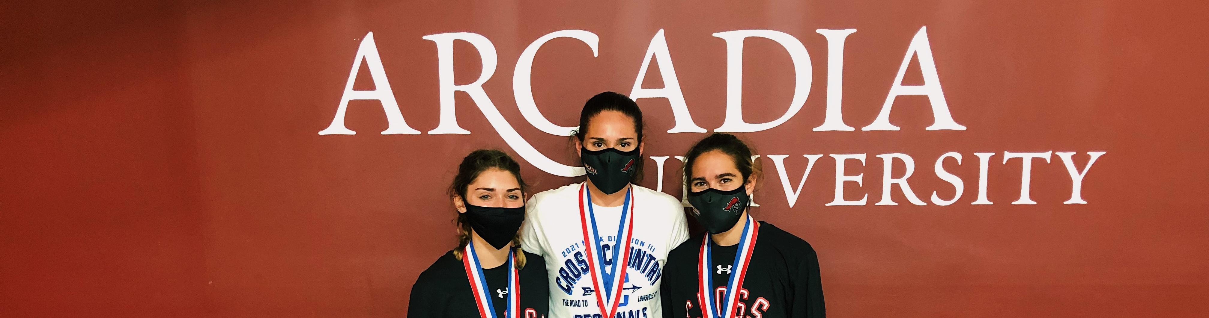 Three masked runners from Arcadia Women's Cross Country with medals around their necks.