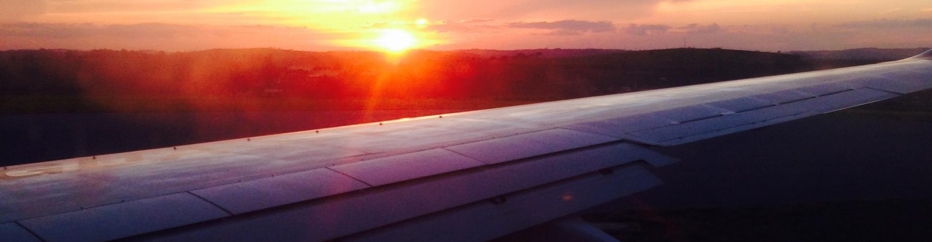 An airplane wing with a sunset in the background