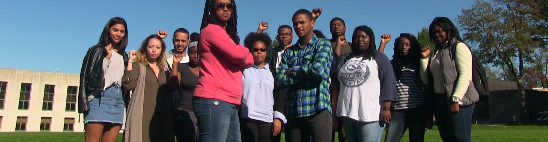 Photo of focused students posing on Haber Green making the power sign.
