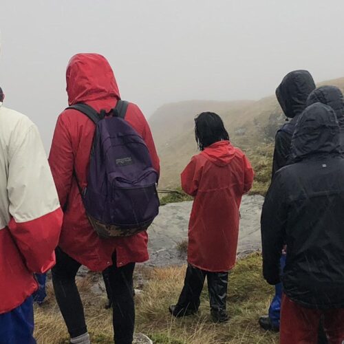 Group of students in jackets walking down hill in Scotland.