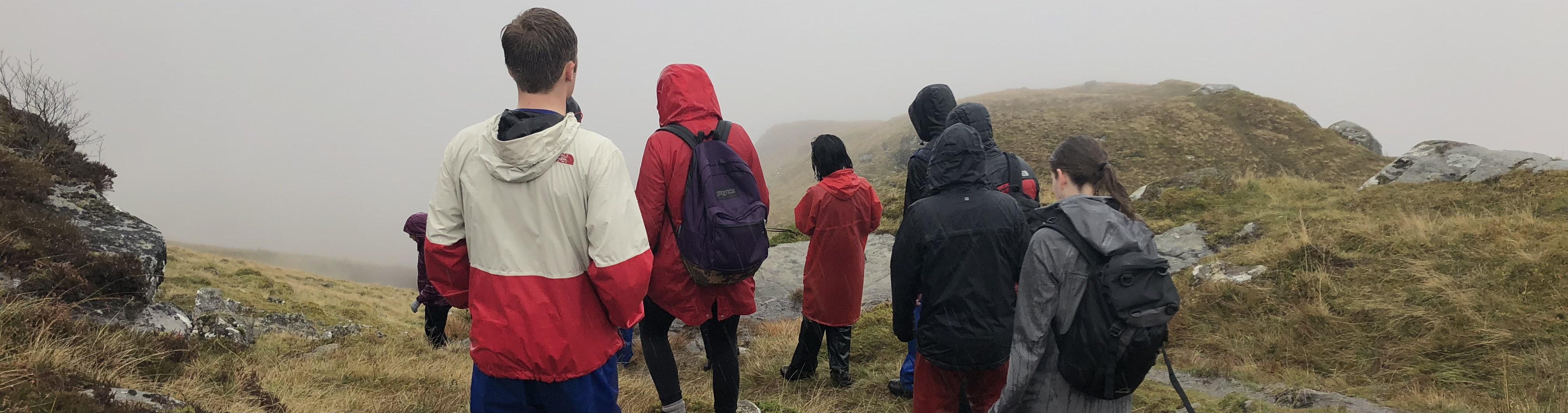 Group of students in jackets walking down hill in Scotland.