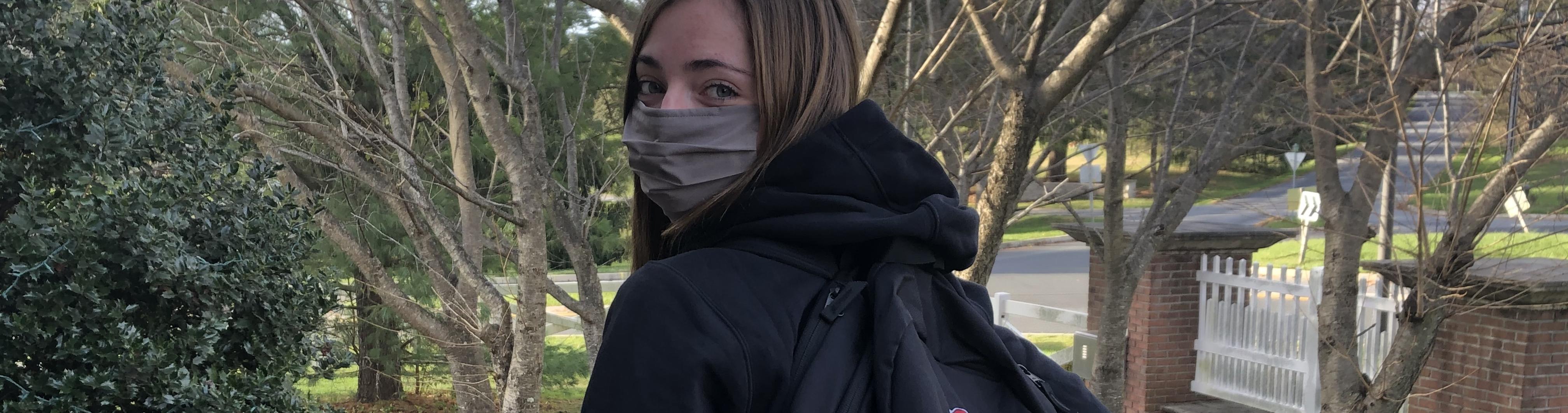 A student wearing a mask looks at the camera