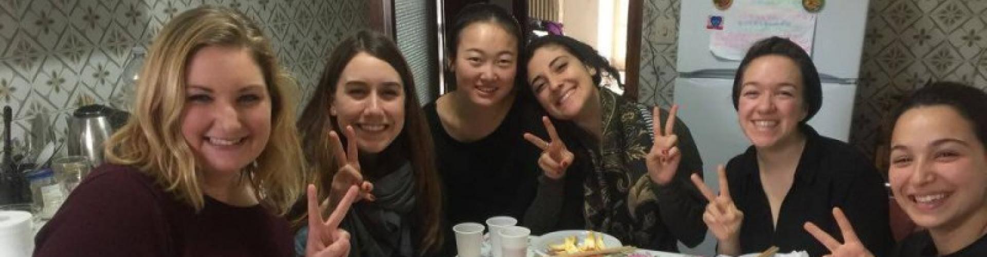 Six students smile at the camera holding up peace signs