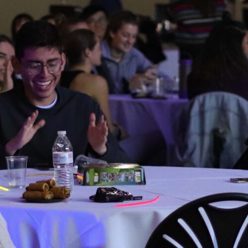 People sitting at tables with glow stick flowers.