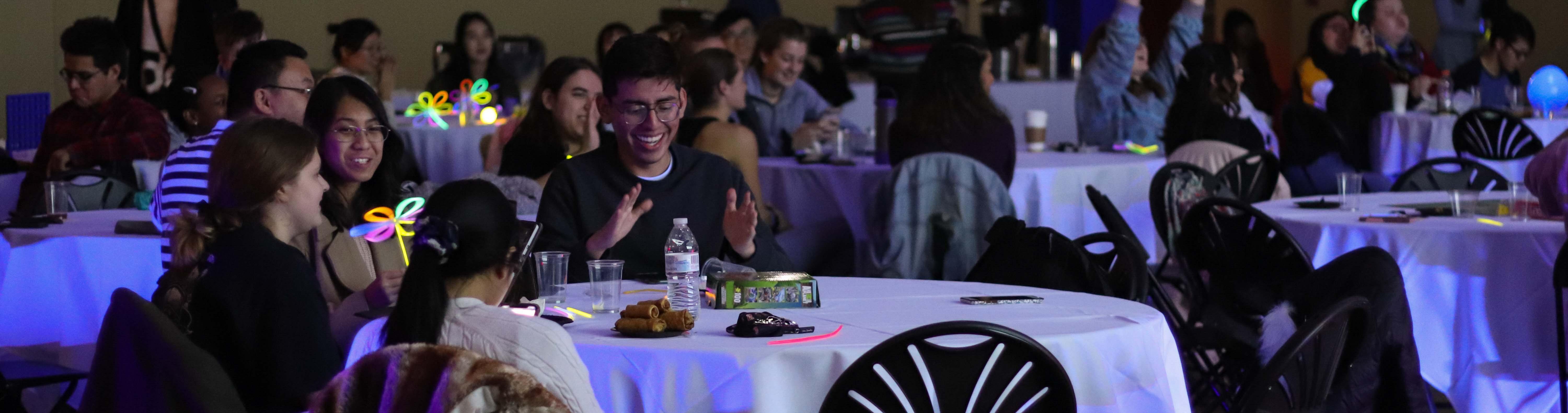 People sitting at tables with glow stick flowers.