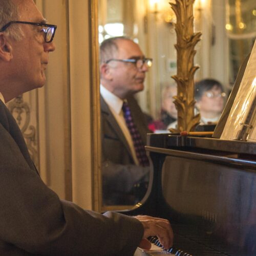 action shot off Samuel Heifetz playing the piano in the Mirror room