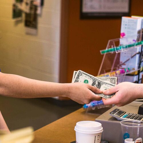 Two people exchanging money at a register.