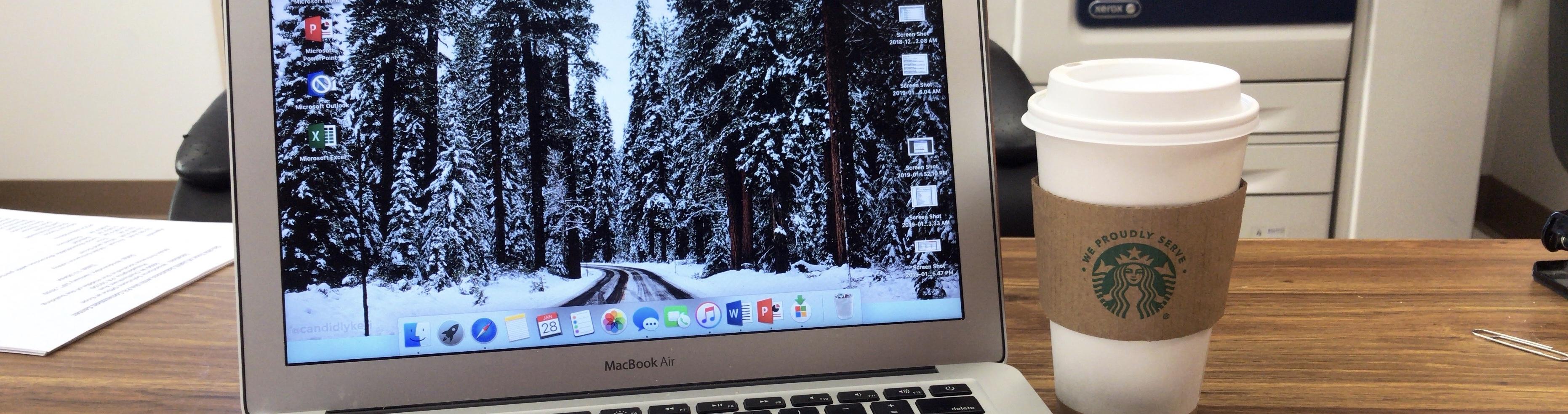 An open laptop with a Starbucks coffee cup next to it