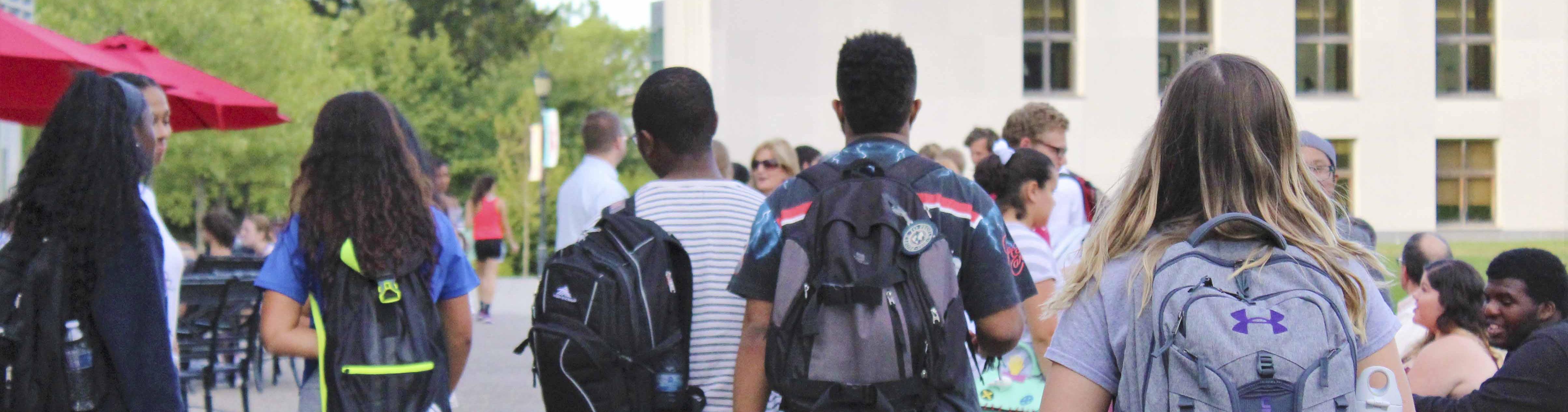 Students walking around campus, wearing backpacks.