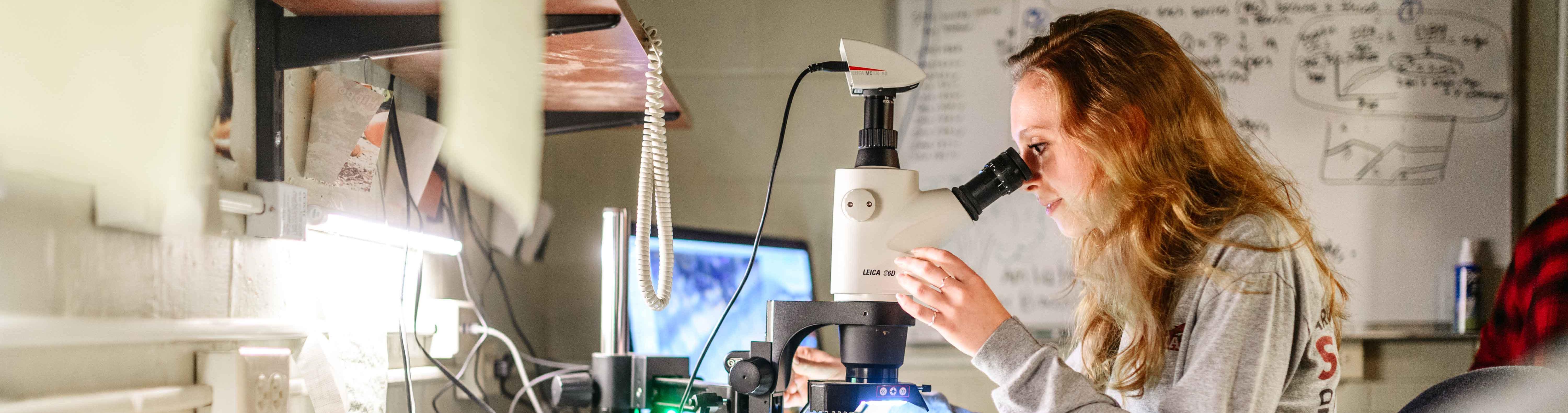 A woman looking into microscope