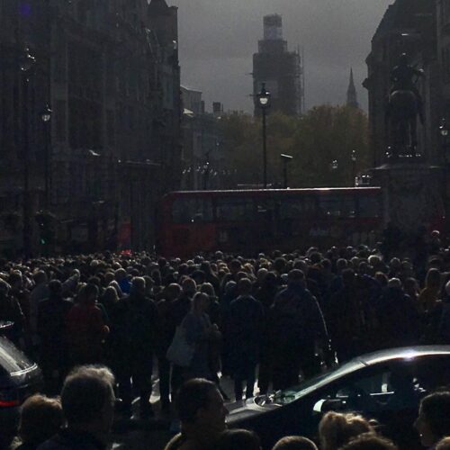 A darken image of a crowd of people in a busy city