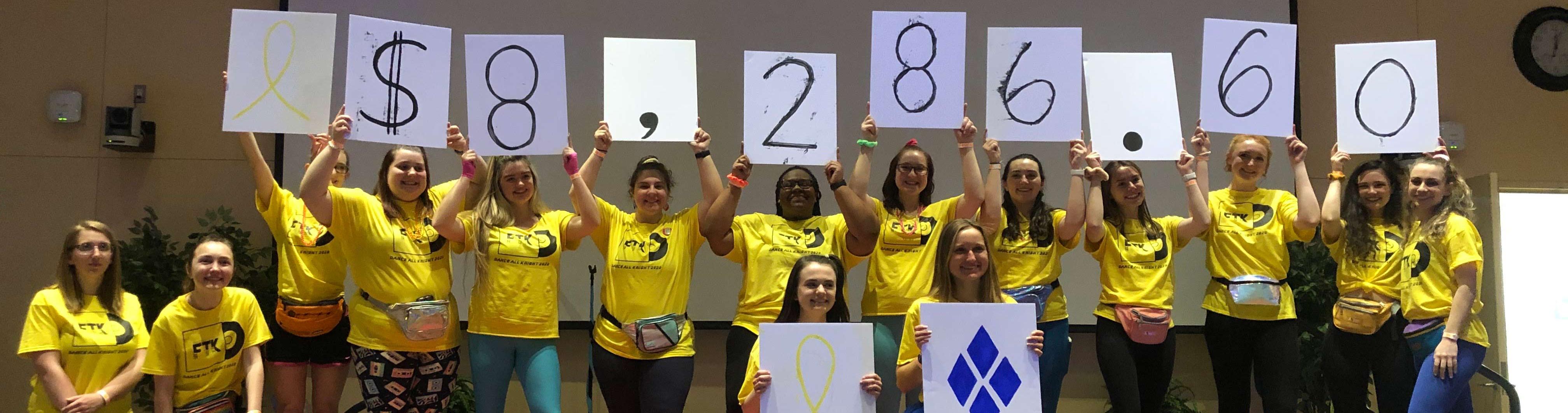 students holding up signs that show how much they raised - $8,286.60~