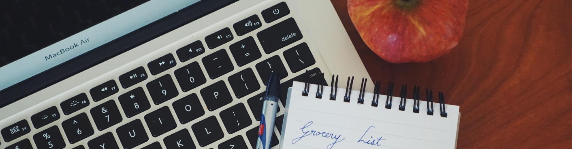 Closeup of MacBook Air and a grocery list.