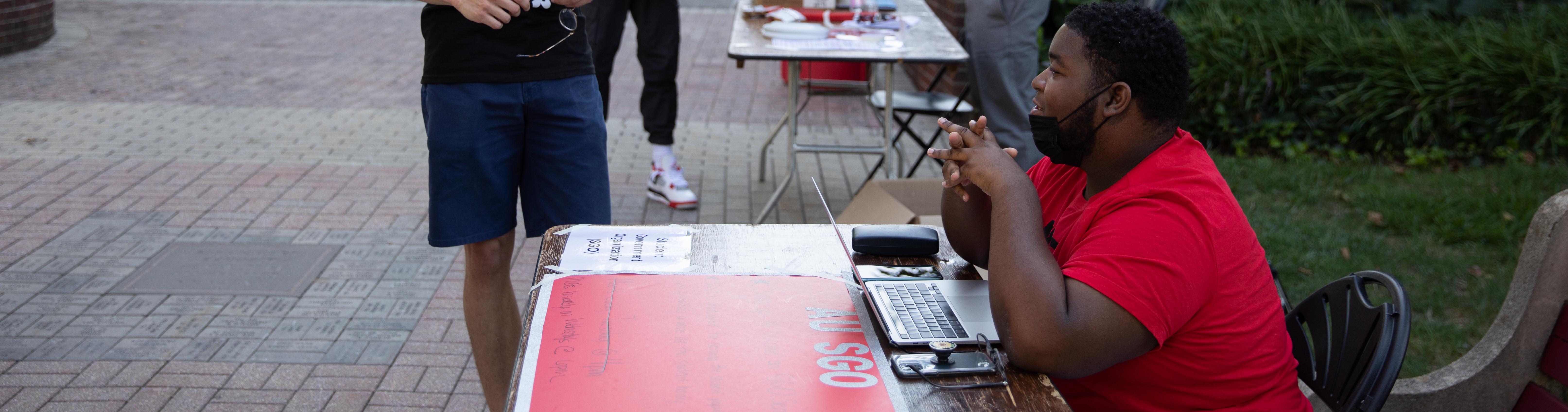 A man sitting at a table on the Walk of Pride