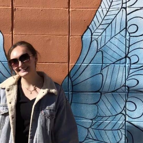 Student standing in front of painted wings.