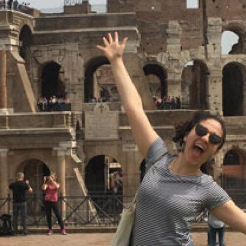 A very happy woman standing in front of the Colosseum