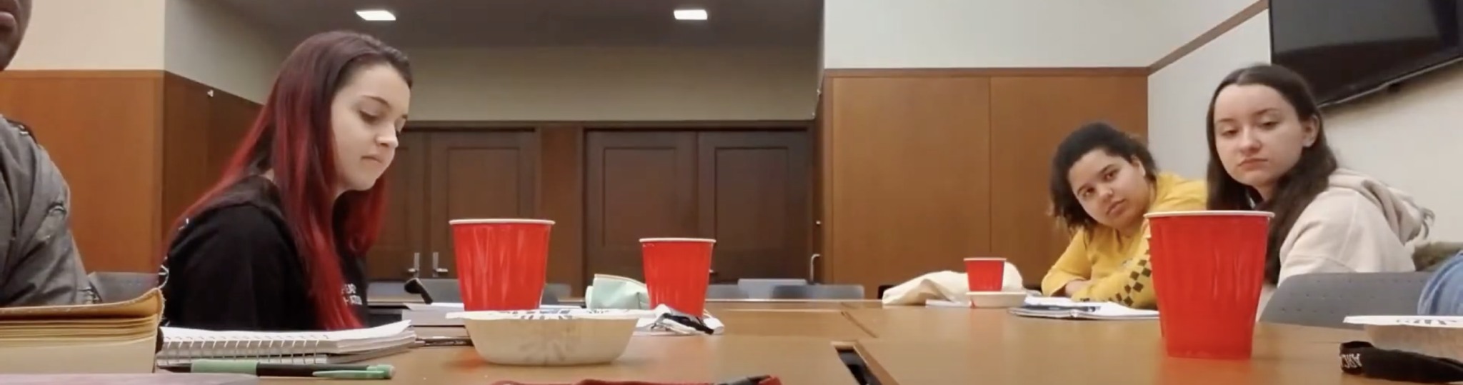 Students sitting at a desk with red plastic cups