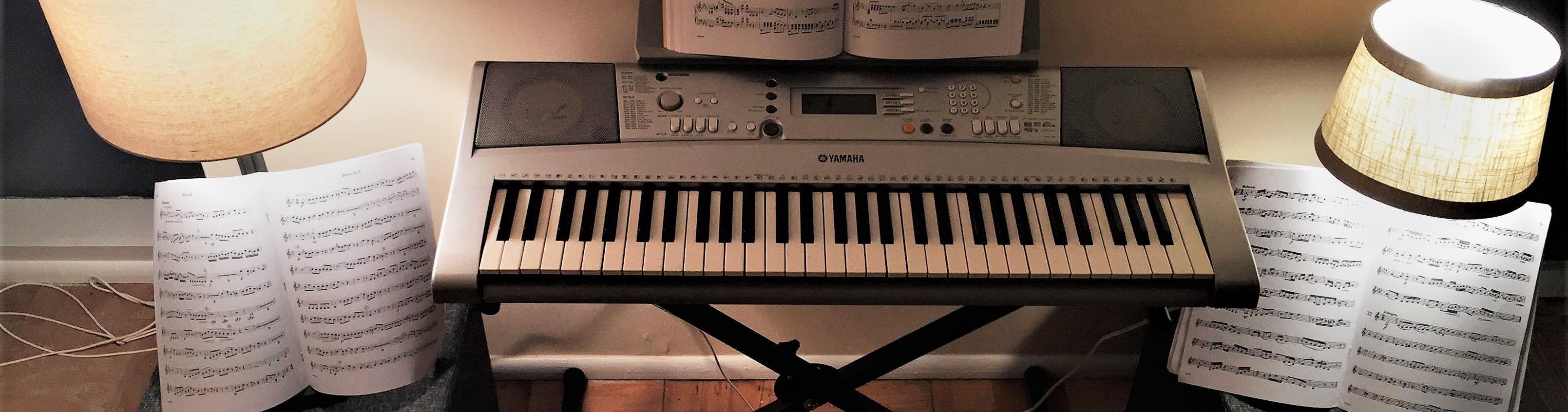 A keyboard with a music book open is flanked by two lamps and two additional music books open.