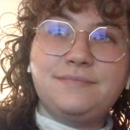 A portrait of a person wearing glasses and with curly hair.