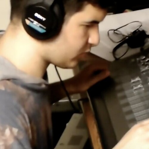 Male student working a sound board with headphones on and hand on sliders