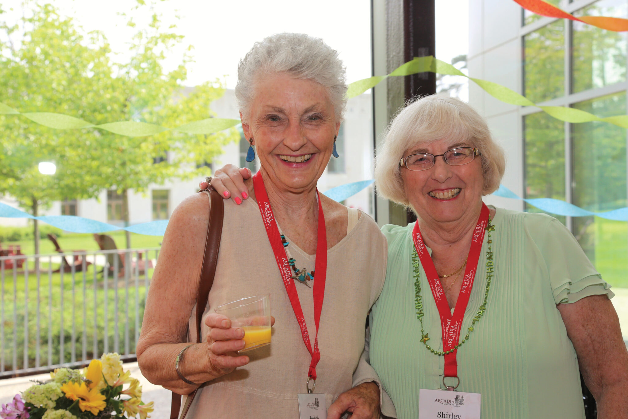 Two alumni students posing together and smiling into the camera