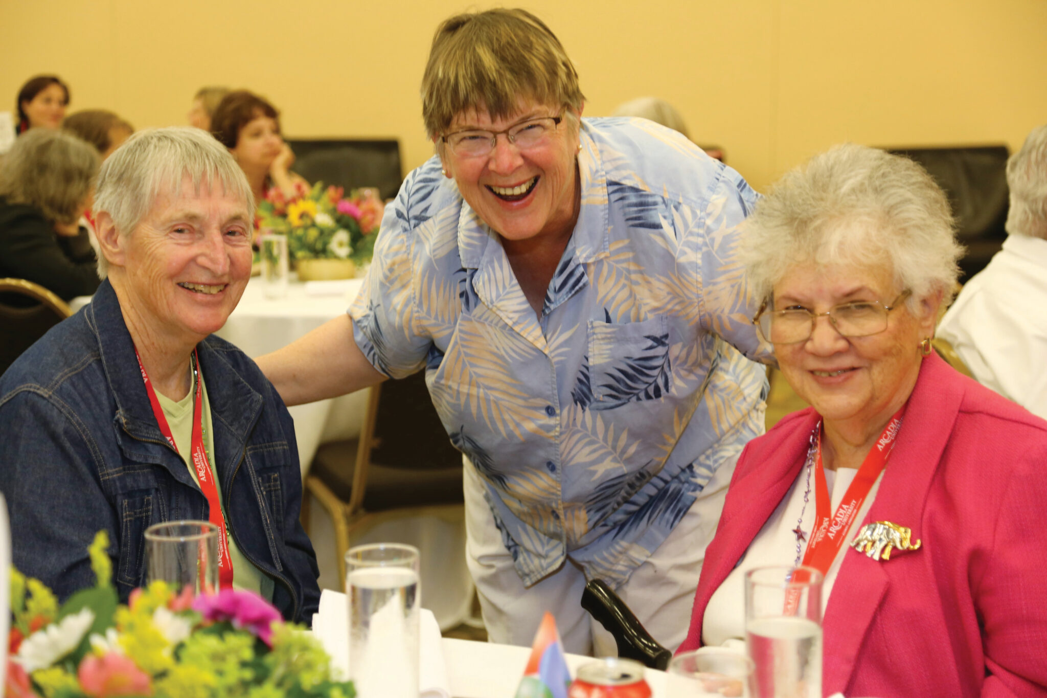 A group of alumni student at a table smiling into the camera