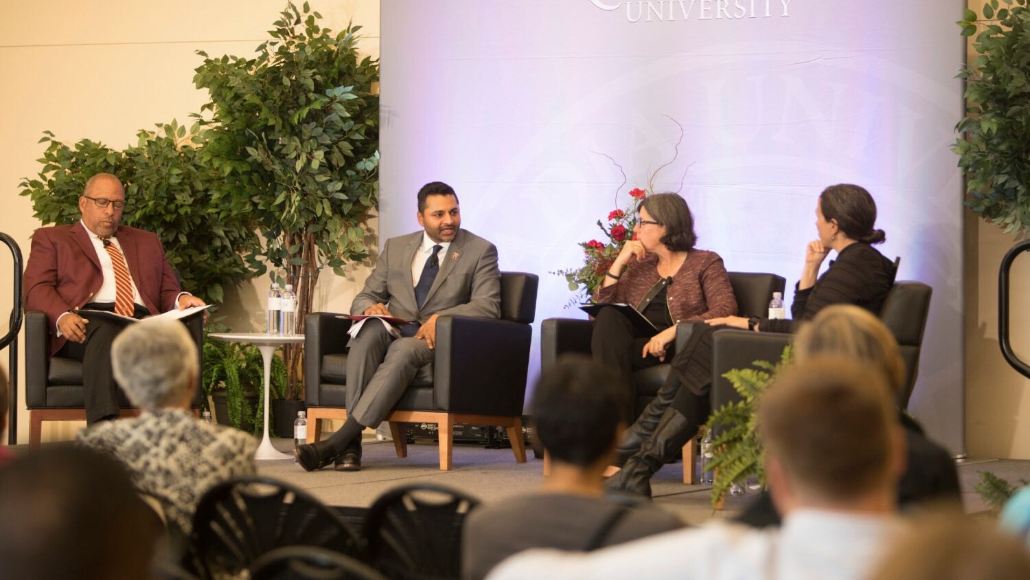 President Nair sits on stage with a panel of speakers