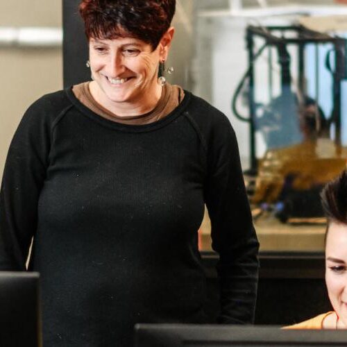 Two students and a professor looking at two computer screens