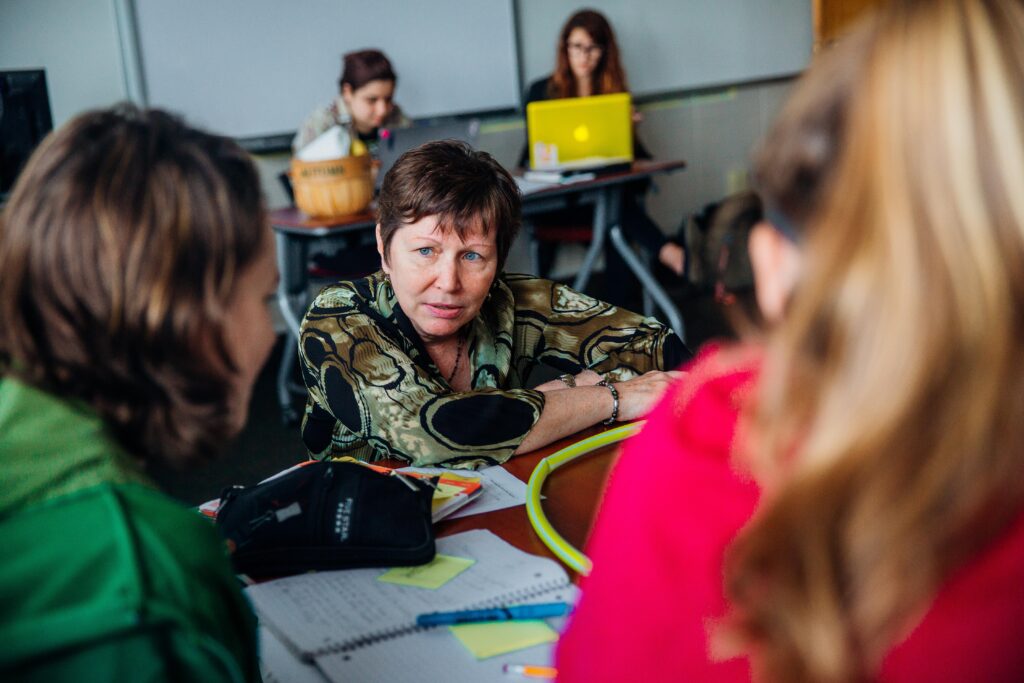 A teacher sitting down to talk to high school students