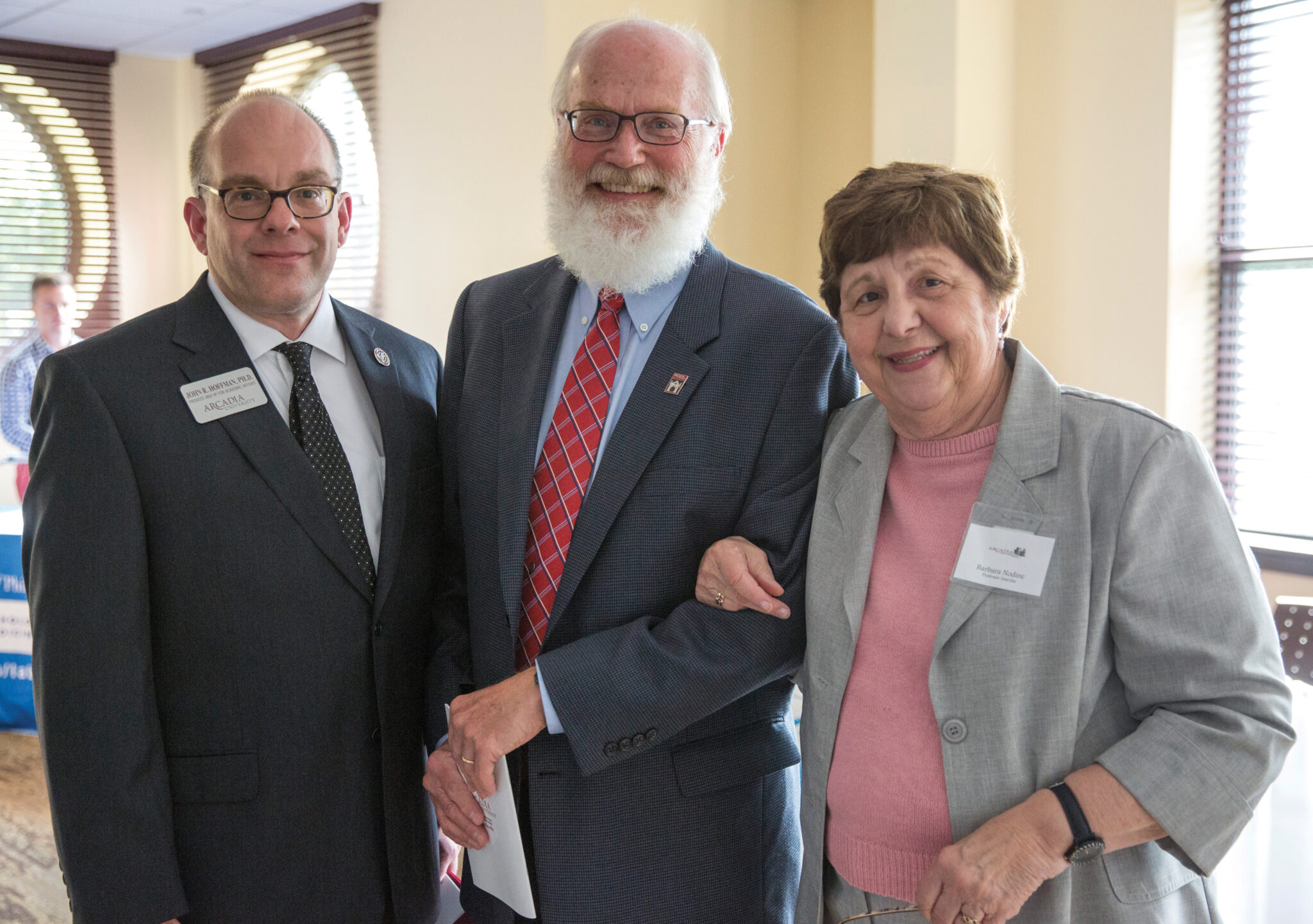 Three people posing together during a formal event