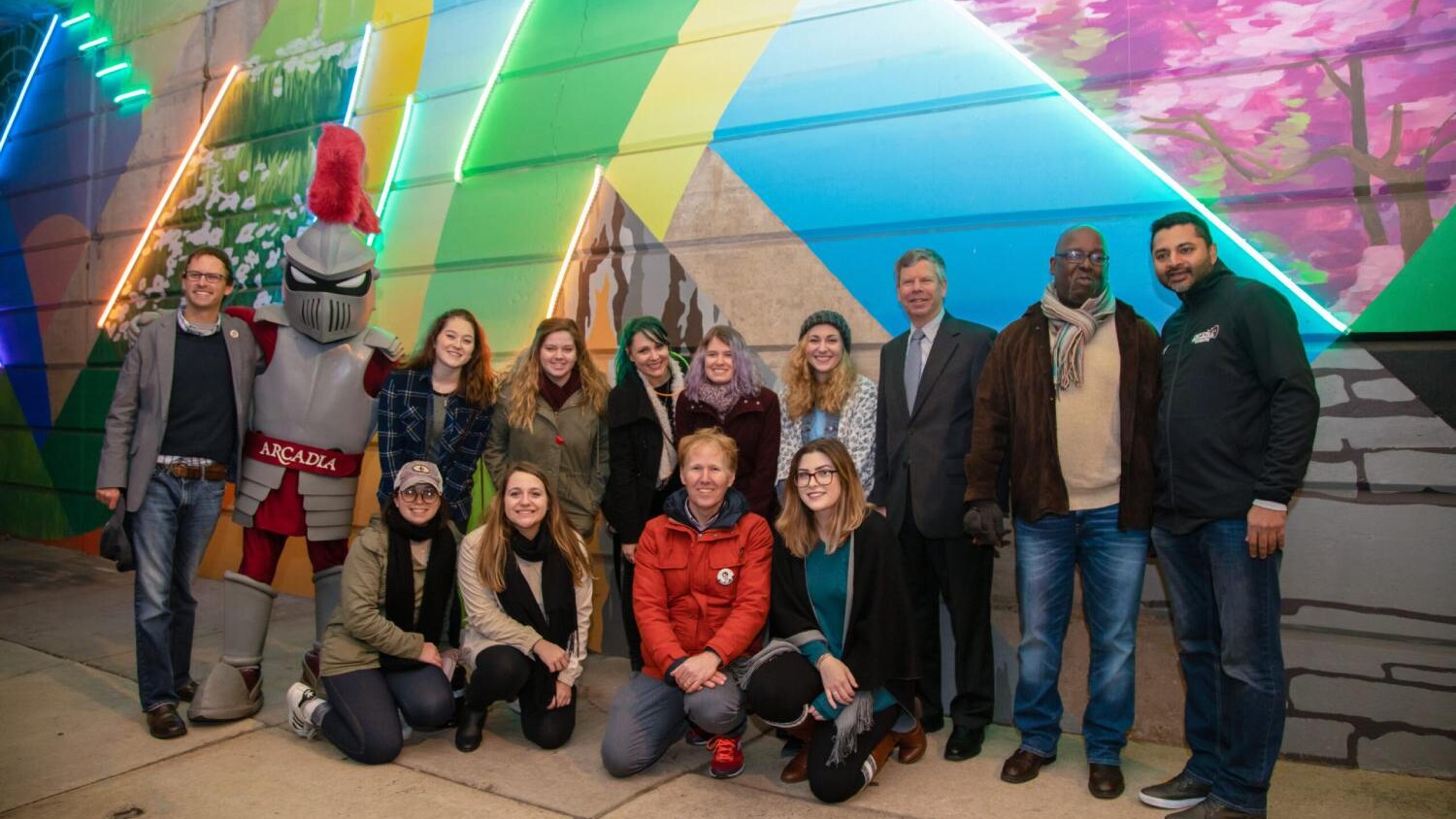 Students and faculty gather at a public art mural