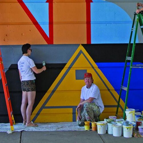 Students paint a mural multi colors as part of Bridging Connections