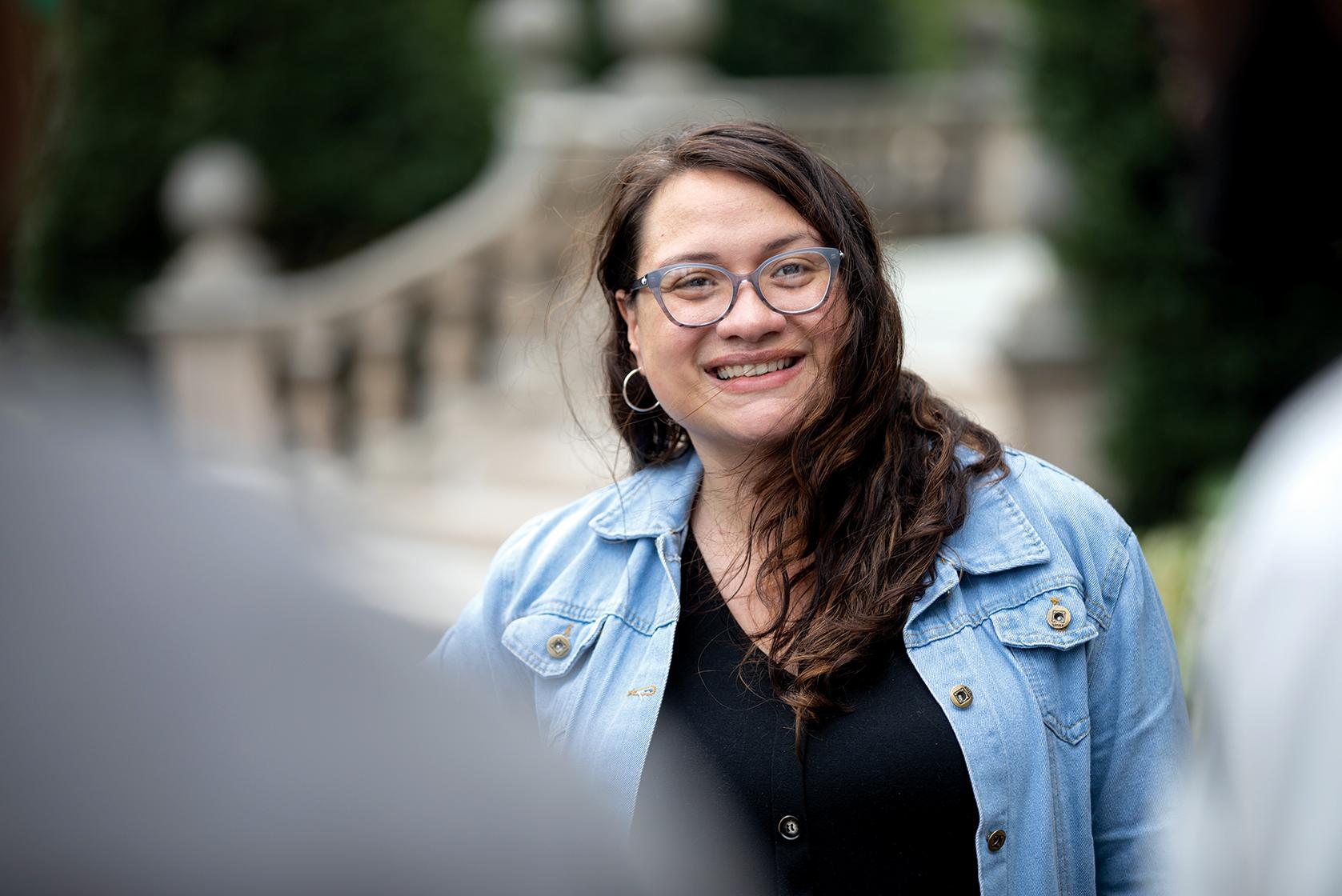 Female student wearing glasses smiles into camera