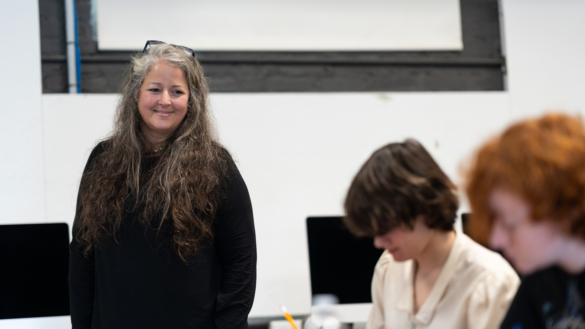 A professor helps undergraduates during an arts class lecture.